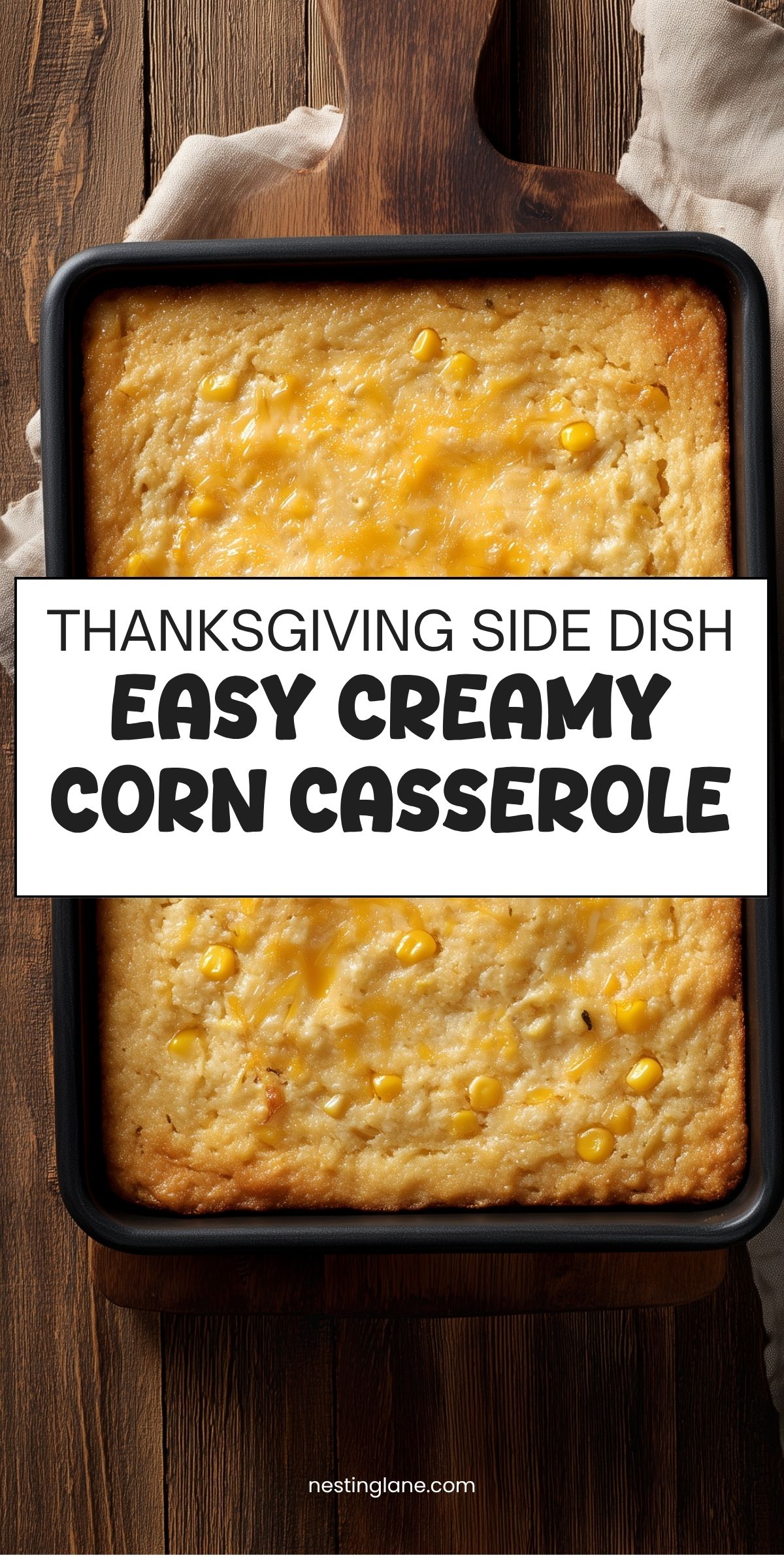 Overhead view of a golden brown creamy corn casserole in a black baking dish on a rustic wooden table. A white text banner reads "THANKSGIVING SIDE DISH EASY CREAMY CORN CASSEROLE" with "nestinglane.com" at the bottom.
